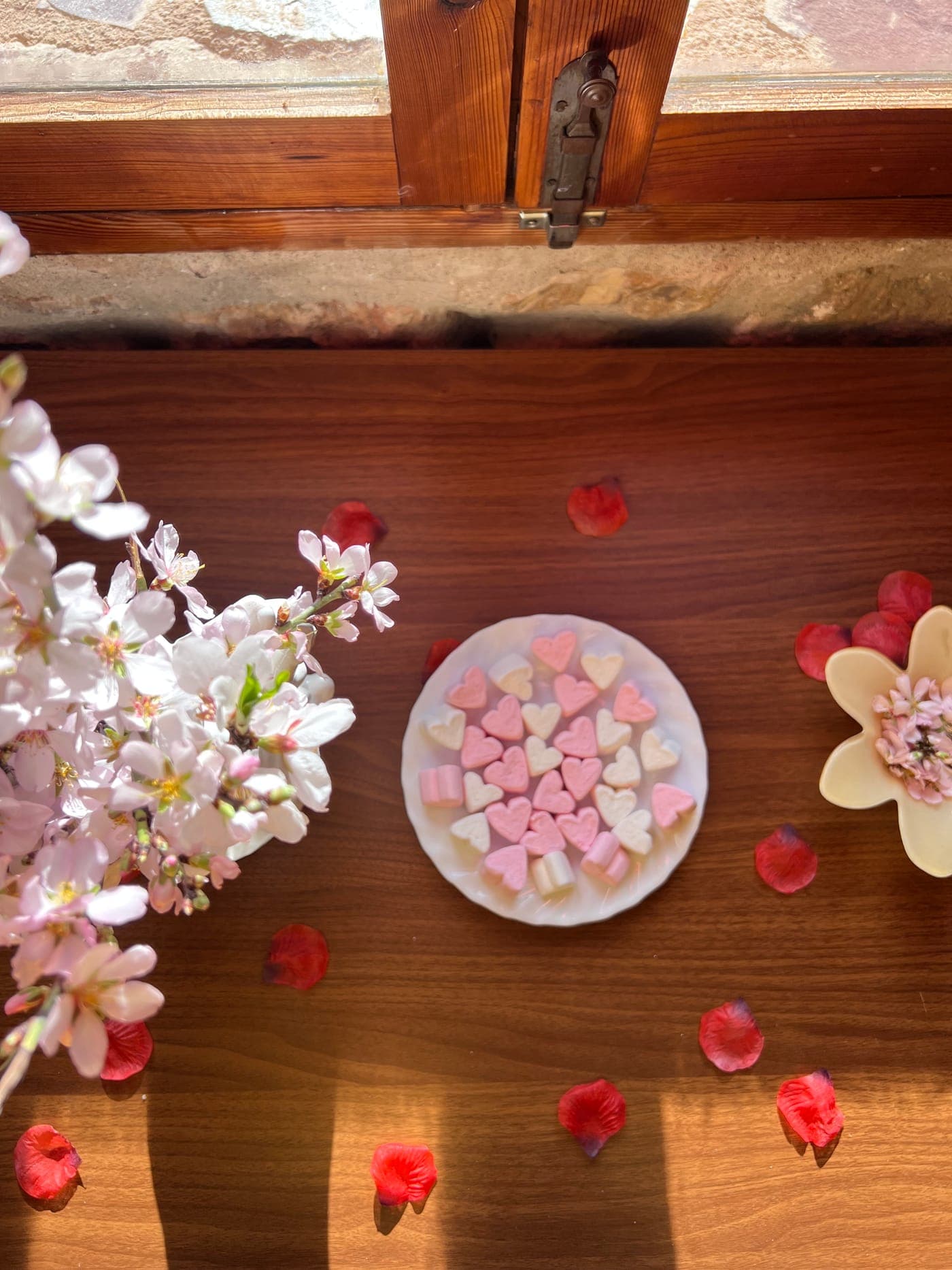 Detalle del pack: rama de almendro en flor y dulces sobre la mesa de madera