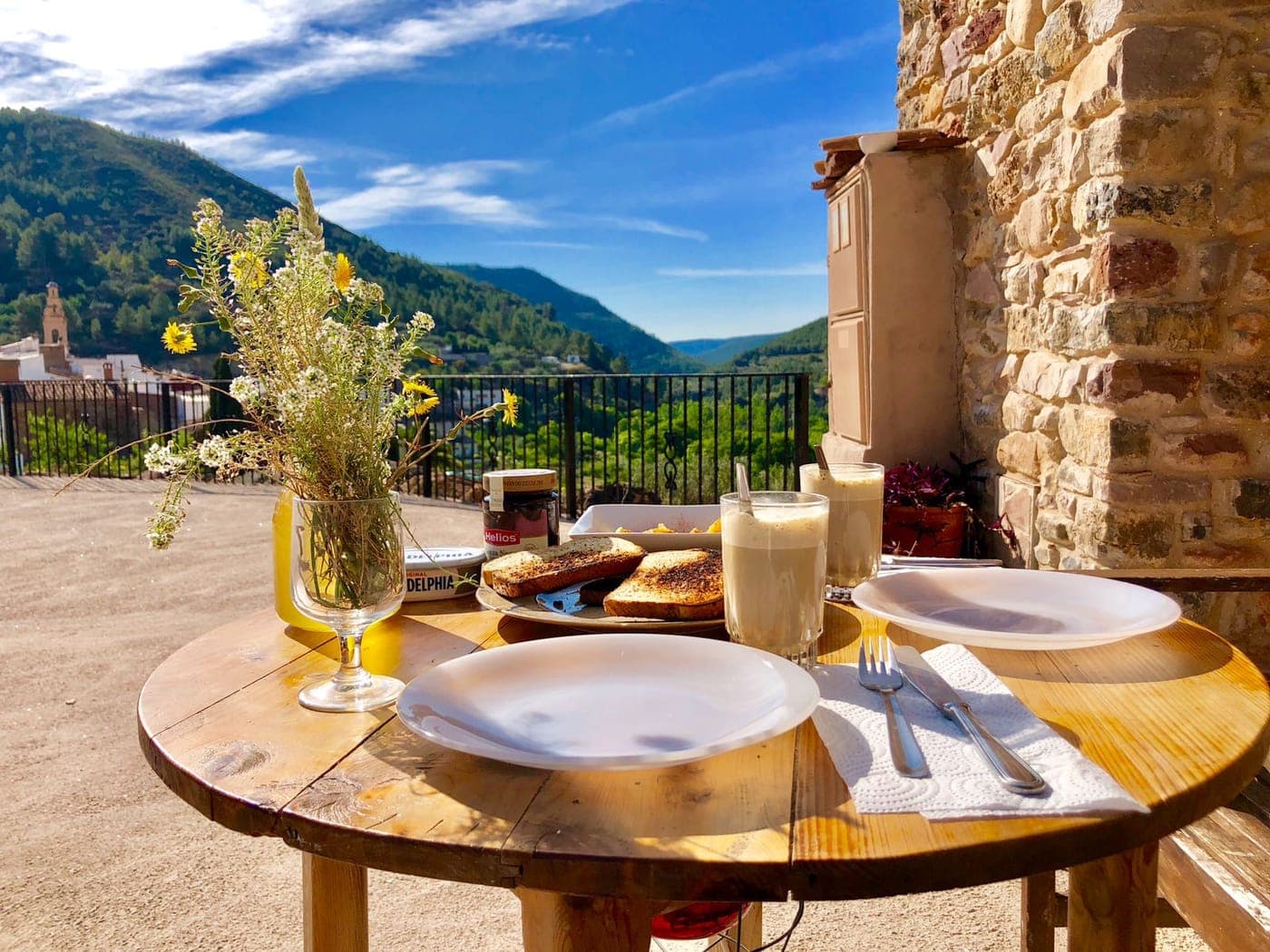 Mesa puesta para desayunar en la terraza con vistas al valle, junto a la casa