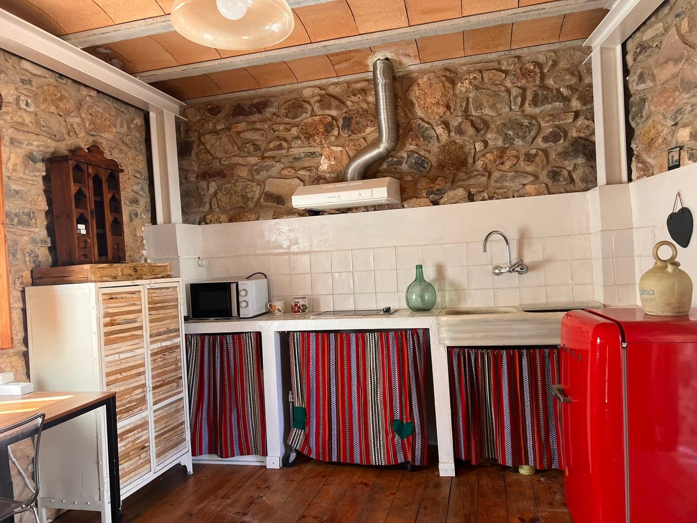 Cocina básica de LaCalma con nevera roja y cortinas de rayas