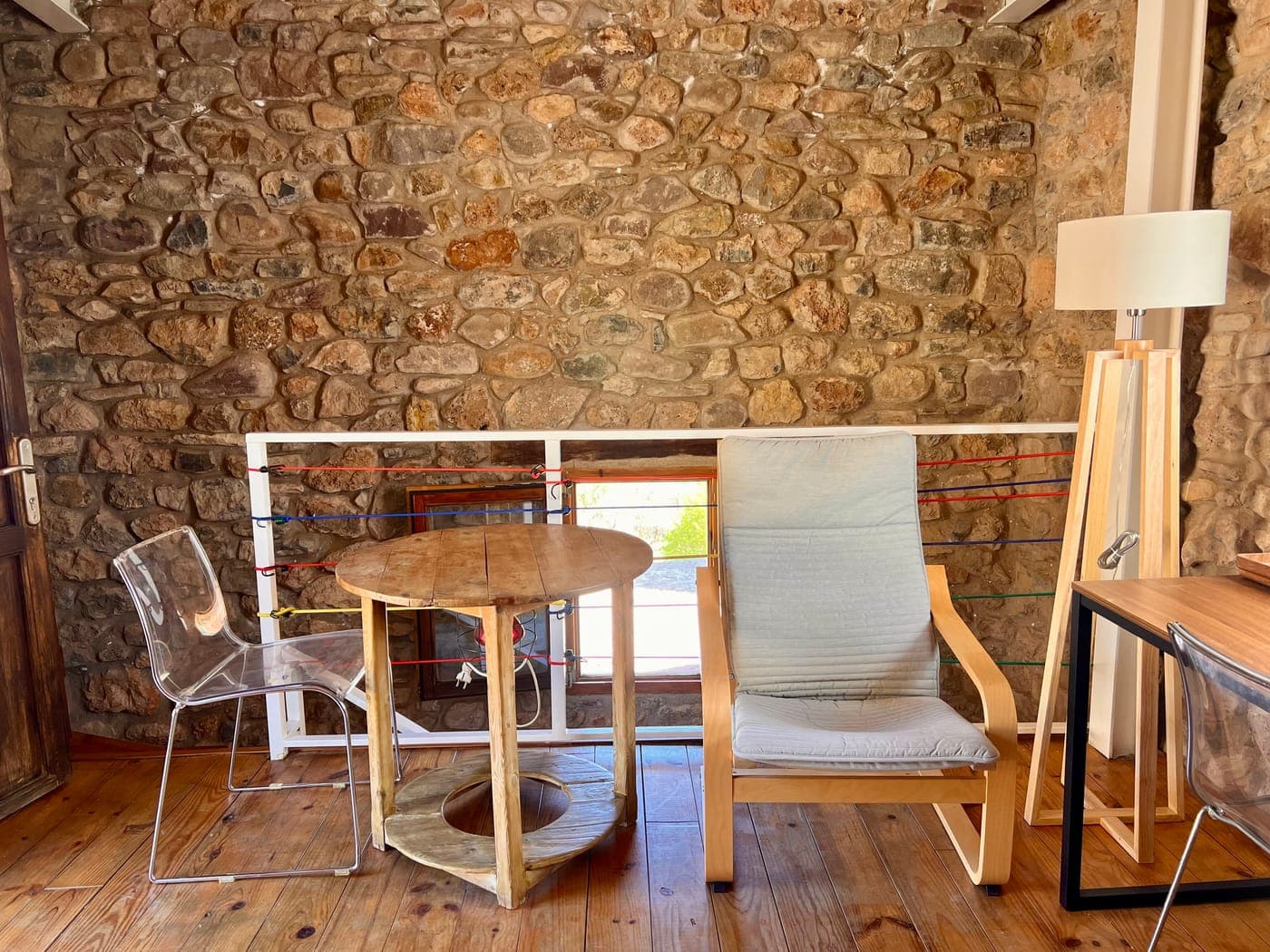 Rincón de la sala de estar con butaca y muro de piedra vista