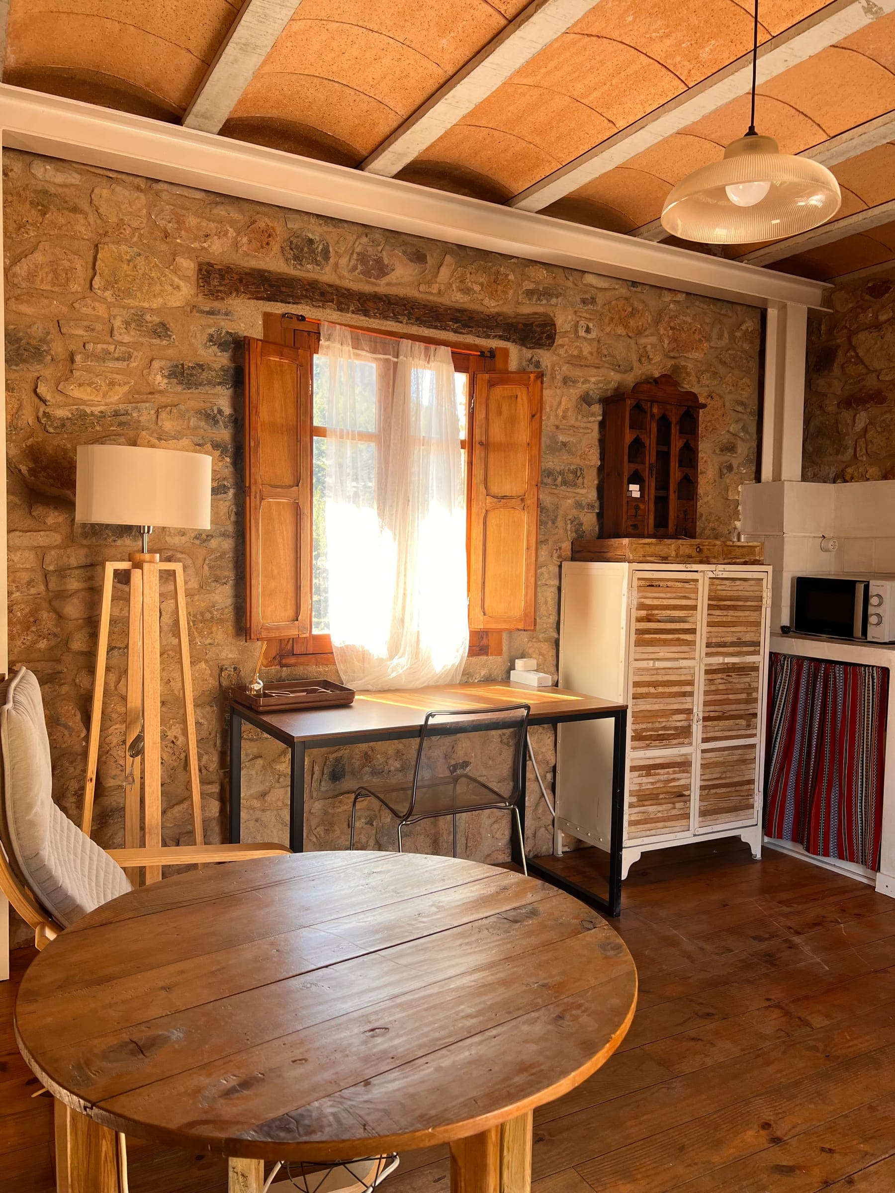 Sala de estar de LaCalma con mesa redonda de madera, paredes de piedra y techo de bovedilla